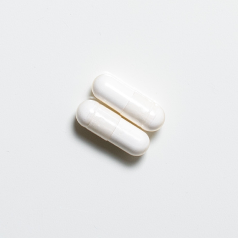 White vegan neotes calcium alpha-ketoglutarate capsules in close-up on a light background