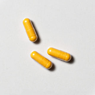 Yellow vegan neotes coenzyme Q10 capsules in close-up on a light background