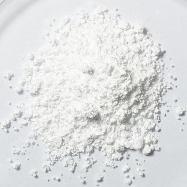 Weißes Focusmind Pro© Pulver mit Kreatin, Niacin und Selen als Close-up auf hellem Hintergrund