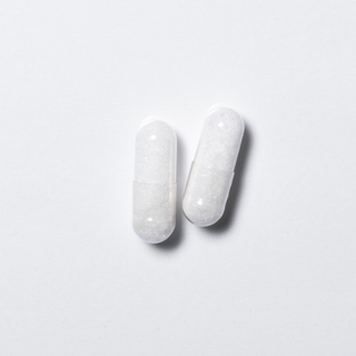 White vegan neotes L-carnitine capsules in close-up on a light background