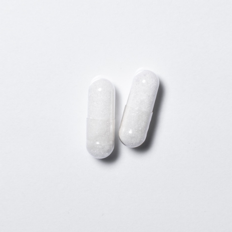 White vegan neotes L-carnitine capsules in close-up on a light background