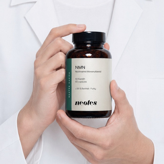 neotes NMN capsules in an amber glass bottle held by a person wearing a lab coat